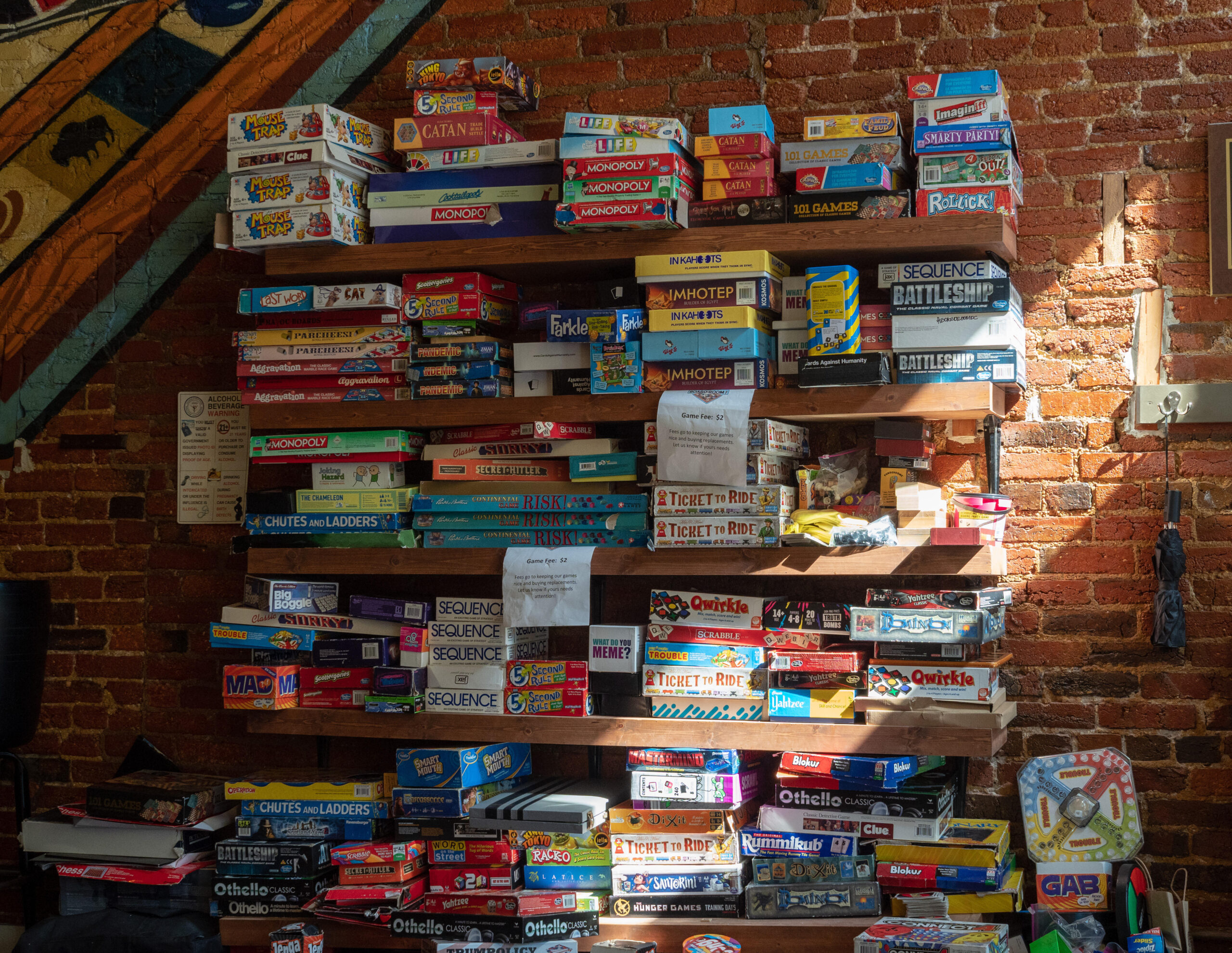 board games stacked on shelves on brick wall to represent the newest addition of Everdell Silverfrost